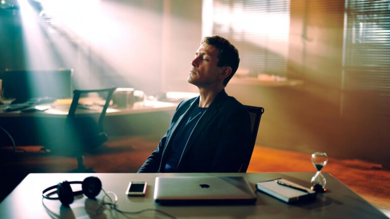 Illustration of a person sitting quietly at a desk, eyes closed and phone muted, taking a brief silent break to reset concentration and improve focus